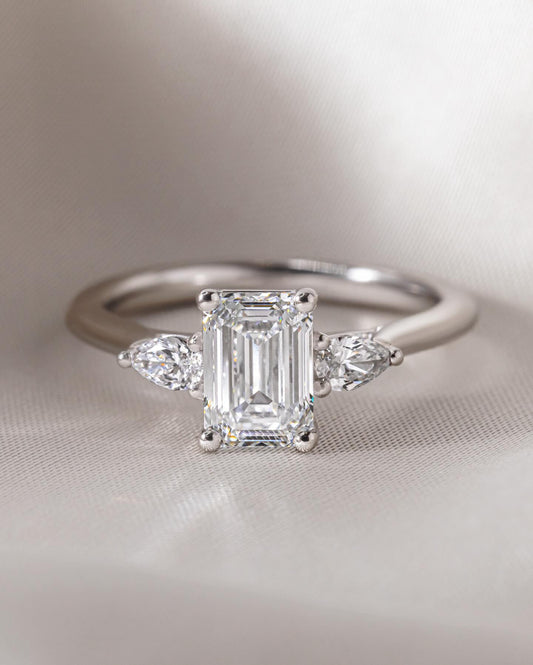 3.5ct Emerald Cut Three Stone Lab Grown Diamond Ring Close-up of an exquisite gold-band ring featuring a diamond, ideal for engagement celebrations or luxury jewelry enthusiasts. The soft manicure enhances the refined and elegant appeal. YouTube Amazon Facebook Weather Google Gmail Wordless WhatsApp Web Translate News blog post ring ceremony Article Life Money 2025 design Ring Ceremony Diamond Shape Diamond Ring Surat Diamond India Market Diamond Ring for Her Diamond Ring for Men Diamond Ring Women 