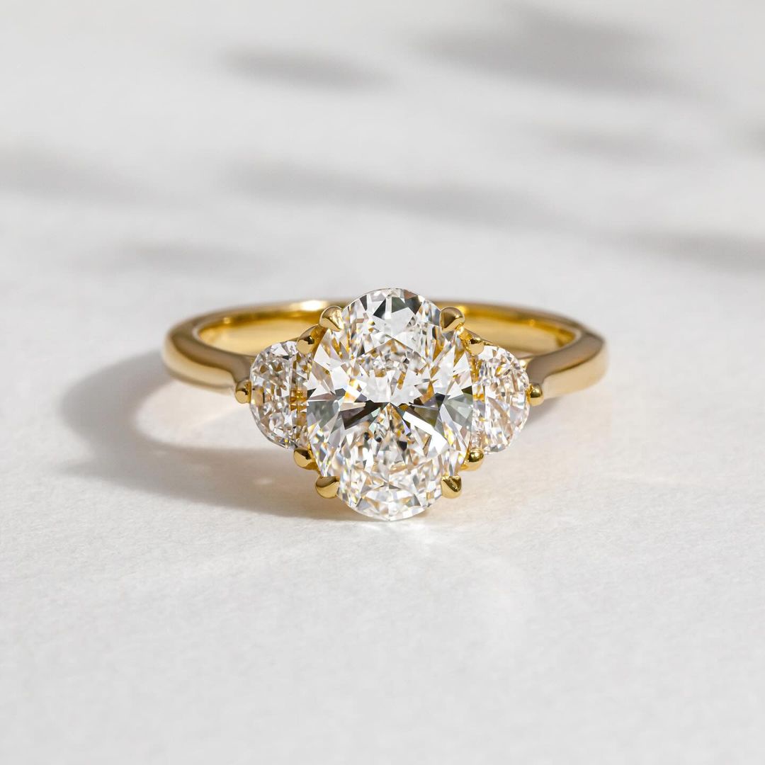 3ct Oval Cut Three Stone Lab Grown Diamond Ring Elegant close-up of a hand showcasing an engagement ring with a gold band, ideal for proposals, weddings, or luxury jewelry collections, paired with a soft, natural manicure. YouTube Amazon Facebook Weather Google Gmail Wordless WhatsApp Web Translate News blog post ring ceremony Article Life Money 2025 design Ring Ceremony Diamond Shape Diamond Ring Surat Diamond India Market Diamond Ring for Her Diamond Ring for Men Diamond Ring Women Engagement Ring Finger 