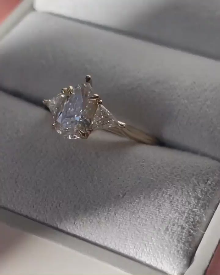4ct Pear Cut With Central Stone With Two Side Trillian Stone Lab Grown Diamond Ring Close-up of an exquisite gold-band ring featuring a diamond, ideal for engagement celebrations or luxury jewelry enthusiasts. The soft manicure enhances the refined and elegant appeal. YouTube Amazon Facebook Weather Google Gmail Wordless WhatsApp Web Translate News blog post ring ceremony Article Life Money 2025 design Ring Ceremony Diamond Shape Diamond Ring Surat Diamond India Market Diamond Ring for Her Diamond Ring  